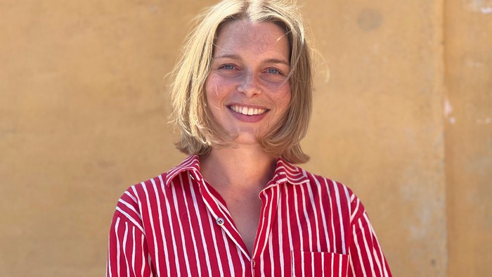 En kvinde med blond hår smiler til kameraet.