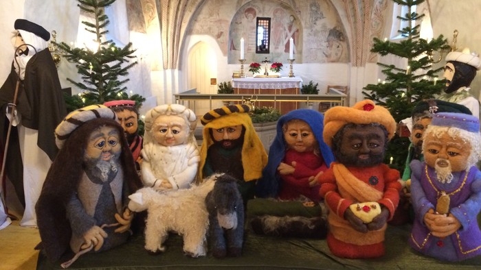 En rekke nisser sidder på alteret i en kirke