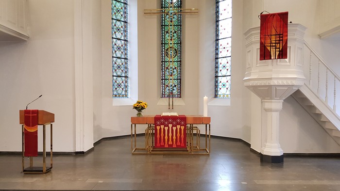 Die Kirche mit farbenfrohen Buntglasfenstern und einem Altar mit roten und goldenen Akzenten