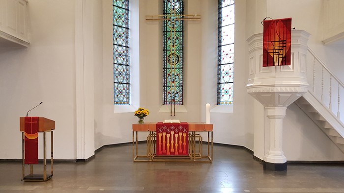 Die Kirche mit farbenfrohen Buntglasfenstern und einem Altar mit roten und goldenen Akzenten
