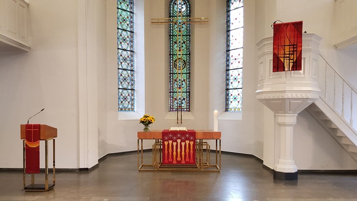 Die Kirche mit farbenfrohen Buntglasfenstern und einem Altar mit roten und goldenen Akzenten