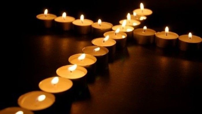 Flere tændte lys arrangeret i et kors.