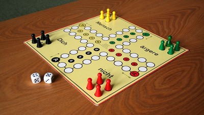 Ein Gesellschaftsspielbrett mit Spielsteinen und Würfeln auf einem Holztisch