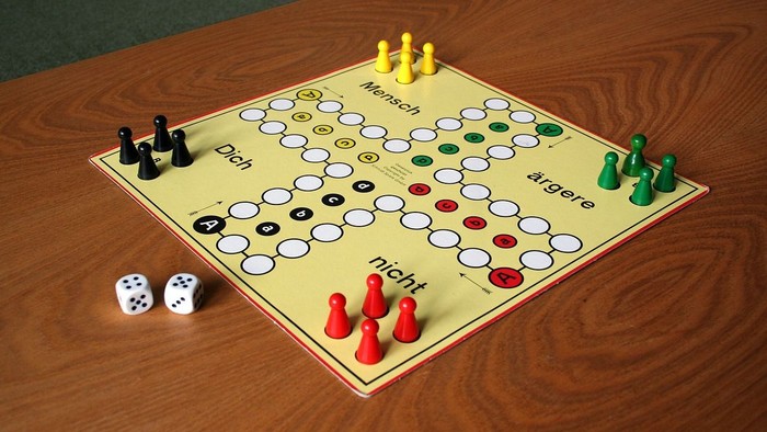 Ein Gesellschaftsspielbrett mit Spielsteinen und Würfeln auf einem Holztisch