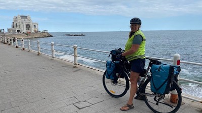 En kvinde med cykel og bagage på en promeneringsvej ved havet