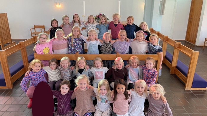 En gruppe børn og voksne samlet i kirke.