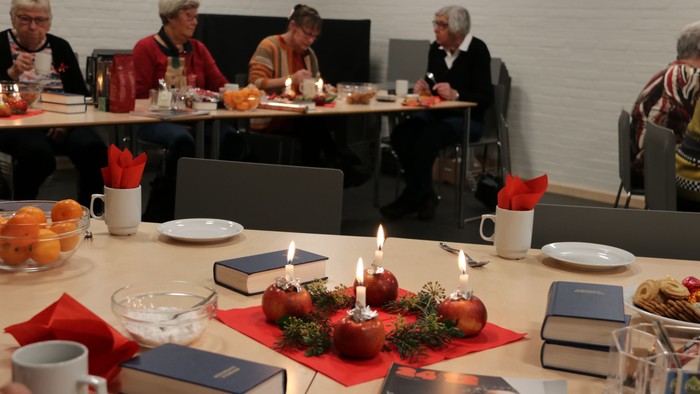 En gruppe mennesker sidder ved bord med mad og drikkevarer.