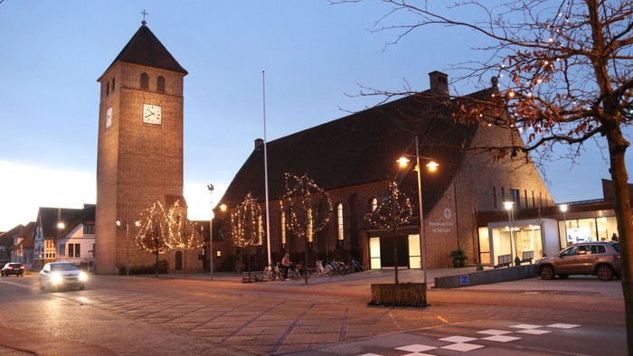 En byplads med et urtårn og festlige lys.