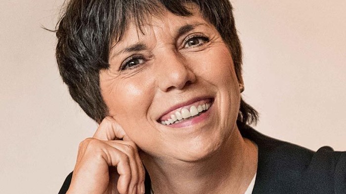 Mittleralte Frau mit kurzen Haaren, lächelnd.