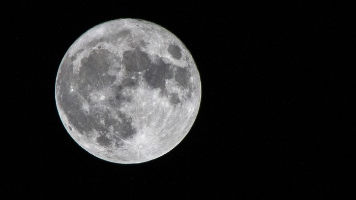 Ein großer, hell erleuchteter Vollmond vor dunklem Nachthimmel.