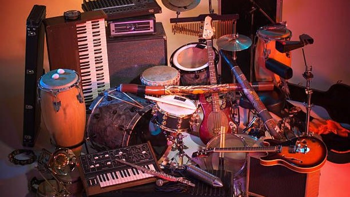 Verschiedene Musikinstrumente und Geräte, darunter Keyboards, Gitarren, Schlagzeuge und Verstärker, sind wahllos angeordnet