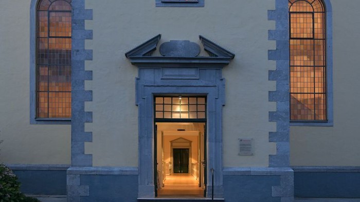 Eleganter Gebäudeeingang mit gewölbten Fenstern, die in der Dämmerung warm leuchten.