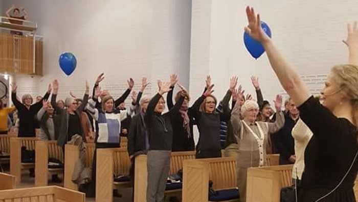 En gruppe af mennesker hygger sig i en hall med blå balloner.
