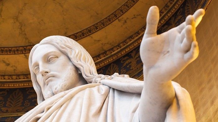 En marmorskulptur af en mand med udstrakt arm.