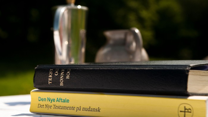 To bøger og en kaffekanne på bord udendørs