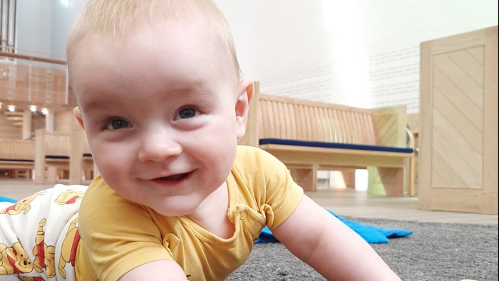 Nærbillede af smilende baby i Vejleå Kirke