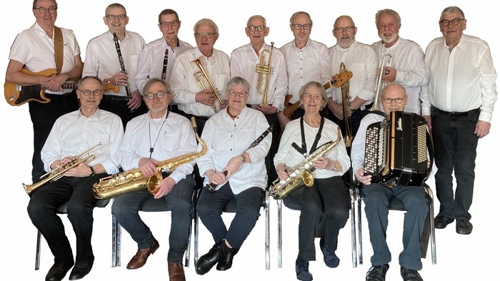 En gruppe ældre musikere poser med forskellige messingblæseinstrumenter og en harmonika.