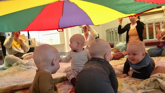 Børn spiller med farverig paraply i legeværelse