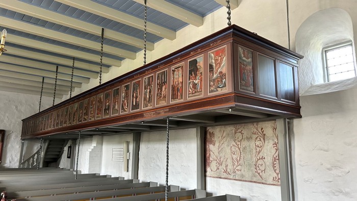 Kirkeinteriør med prædikestol i udskåret træ og gobelin.