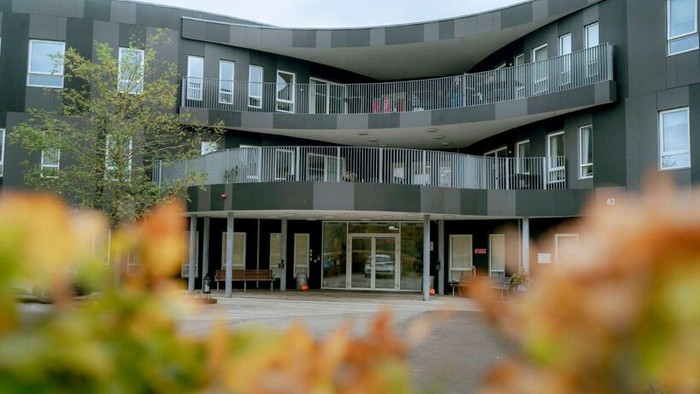 Moderne bygning med balkoner og træer foran
