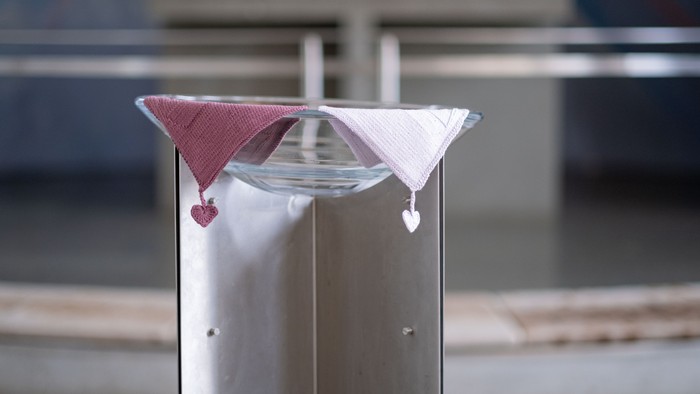 En metallisk post med to papirfjer i røde og hvide farver.