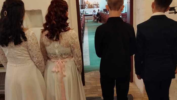 Fire børn står i en kirkegang og ser ind i kirkerummet