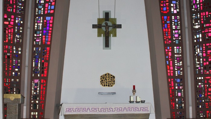 Die Kirche mit Altarraum, Kreuz und buntem Glasfenster