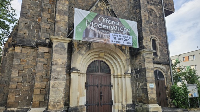Altes Kirchgebäude mit Werbung für Offene Friedenskirche.