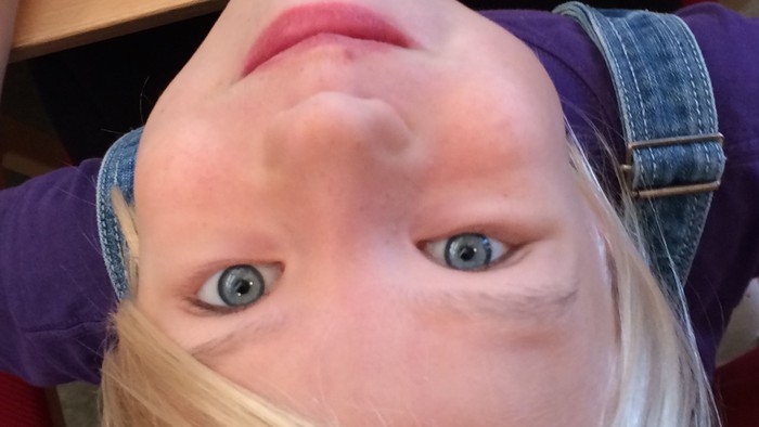 Et barn med blond hår ser op i kameraet.