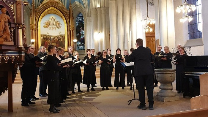 En kor sang i en kirke med høje arkiter.