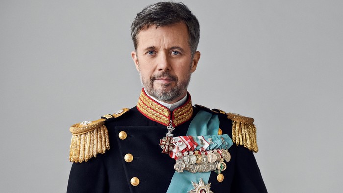 En mand i formel militæruniform med guldbeslag og ordenstegn.