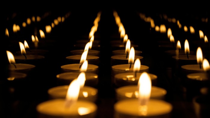 Reihen von brennenden Kerzen in einem schwach beleuchteten Raum.