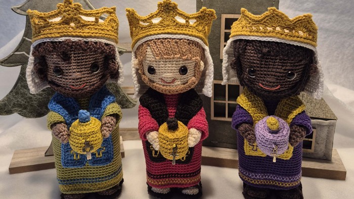 Tre knuste konger med kroner og skjold foran en lille hytte og snestjerne