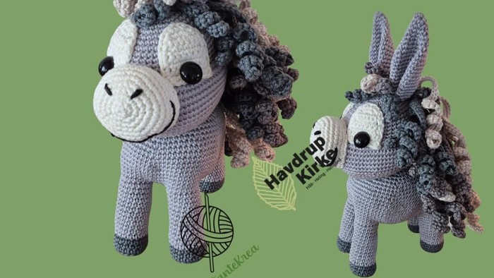 Håndstrikkede hækelæsser i form af æsler med farverige, fluffy maner og haler, udstillet på grøn baggrund.