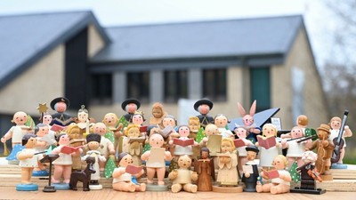 Eine große Gruppe von Holzfiguren steht vor einem Haus.