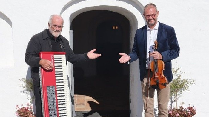 To men med musikinstrumenter udenfor hvid bygning