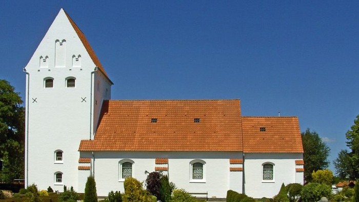 Et hvidt klokketårn med røde tag og omgivelser