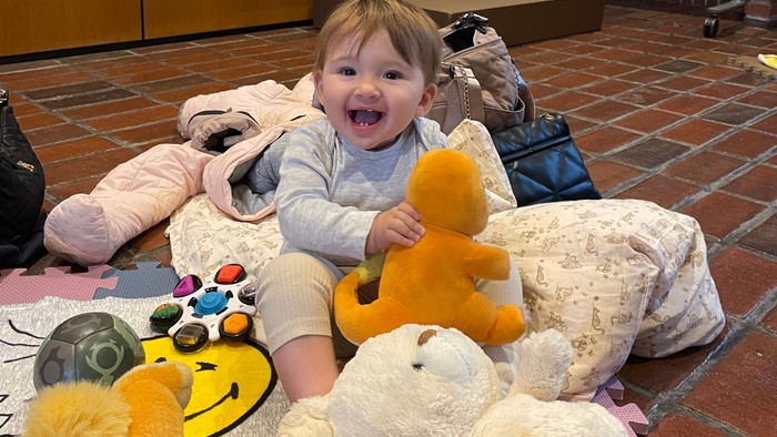 Barn sidder med bamser på legetæppe.