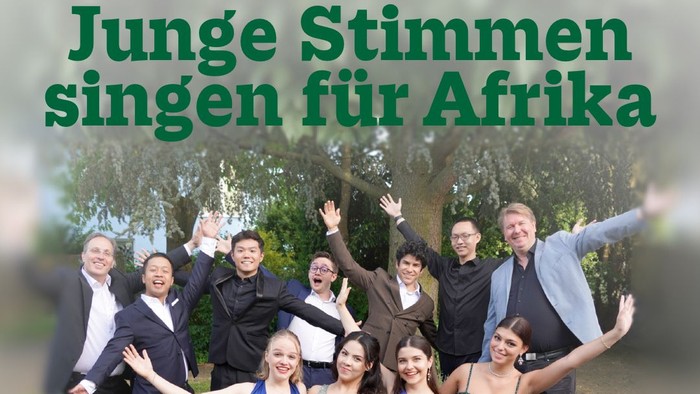 Eine fröhliche Gruppe junger Sänger posiert freudig mit erhobenen Armen für eine Benefizveranstaltung zur Unterstützung Afrikas.