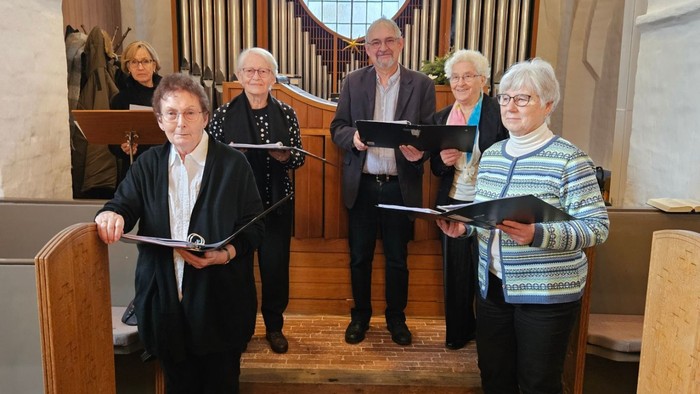 En gruppe af mænd og kvinder står i en kirke og holder noter