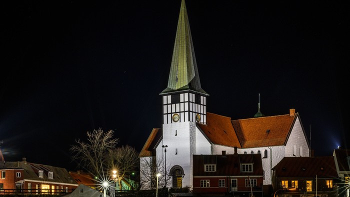En kirke med tårn og et skip i vandet ved nat