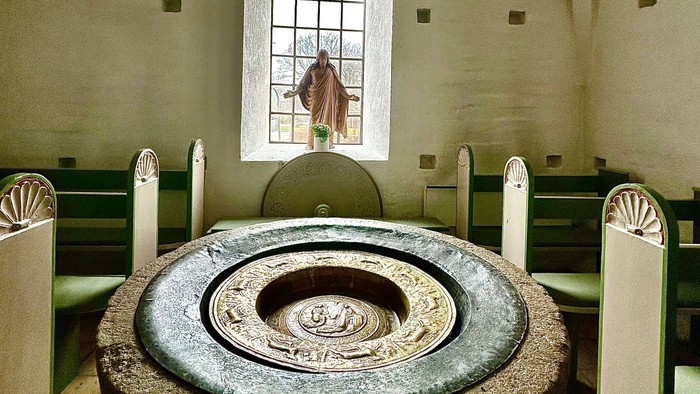En kirke med en stor stenfont og hvidt bænke.