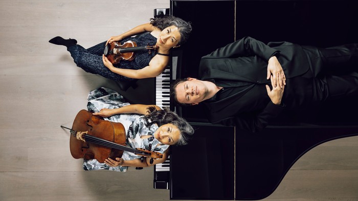 En kvinde og to mænd spiller på piano, violin og cello i et studie.