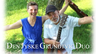En glade duo spiller guitar under et træ
