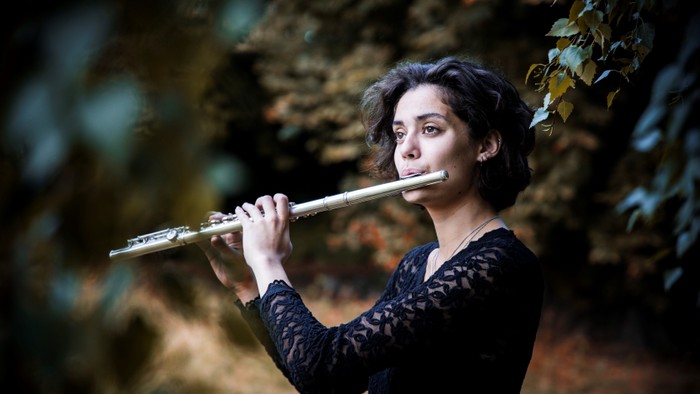 En kvinde spiller fløjte i en skovmiljø.