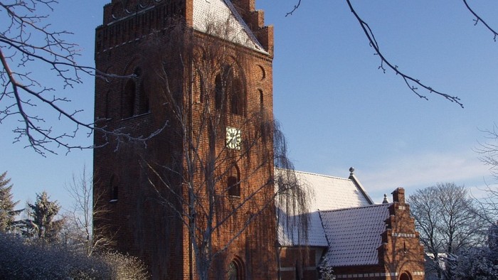 En isøret kirke med tårn i sneklædt landskab