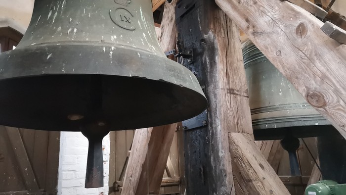 Toppen af en stor, grøn klokke i et tømret klokketårn