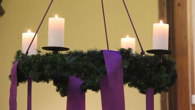 En kranse med lys og violet bånd.