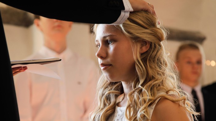 En ung pige med bløde bølger i håret ser sig selv i spejlet.