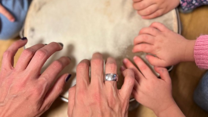 Mehrere Hände greifen nach einem weißen Objekt auf einem Tisch.